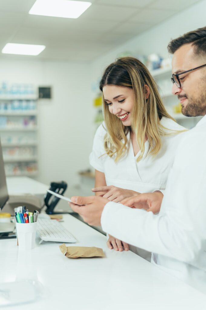 Happy young male and female colleagues pharmacist working in a pharmacy